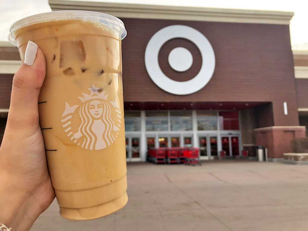 A person holding a Starbucks drink in front of a Target